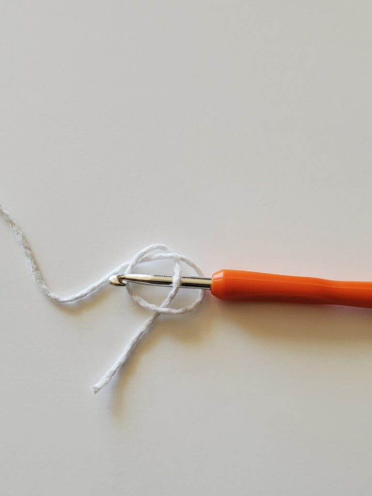 Crochet hook inserted under yarn tail
