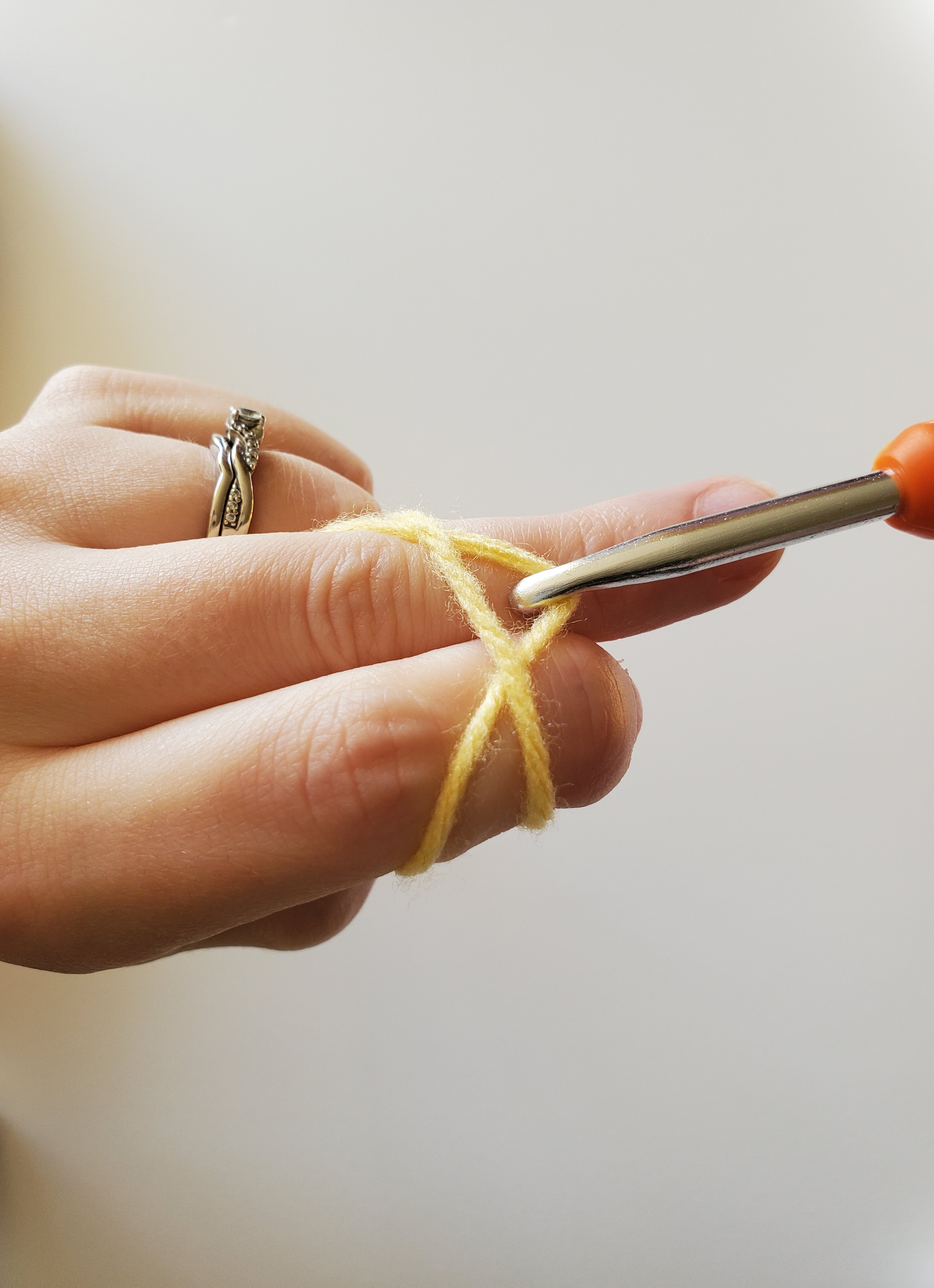 Pulling the second strand of yarn underneath the first strand