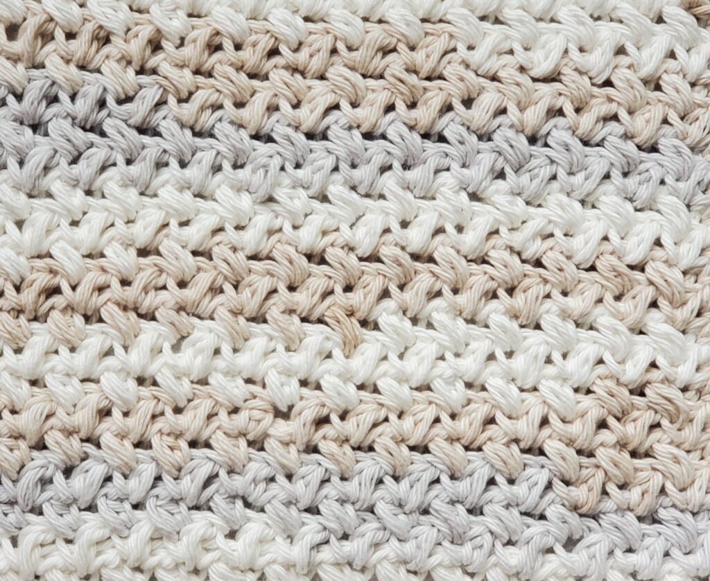 Close up of bean stitch dishcloth with peaches and creme stripey linen