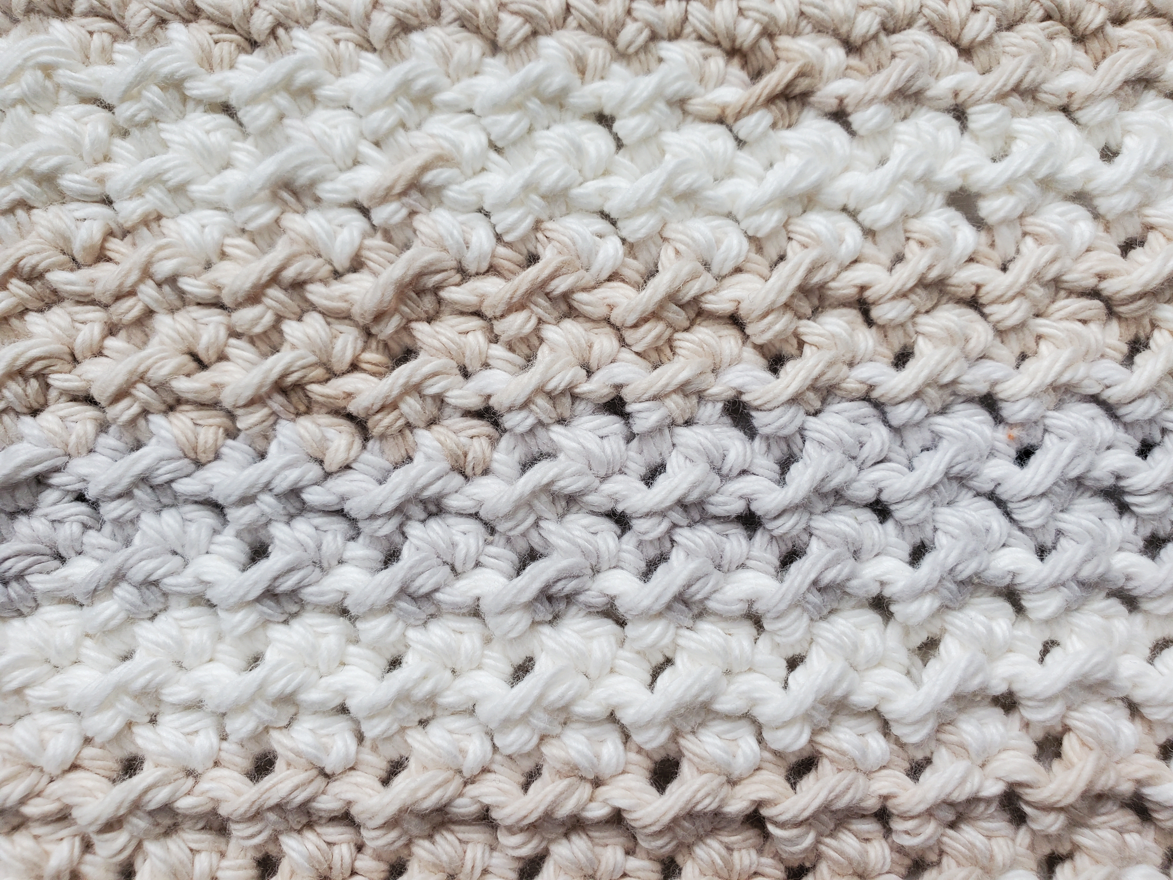 Close up of crunchy stitch dishcloth with peaches and creme stripey linen