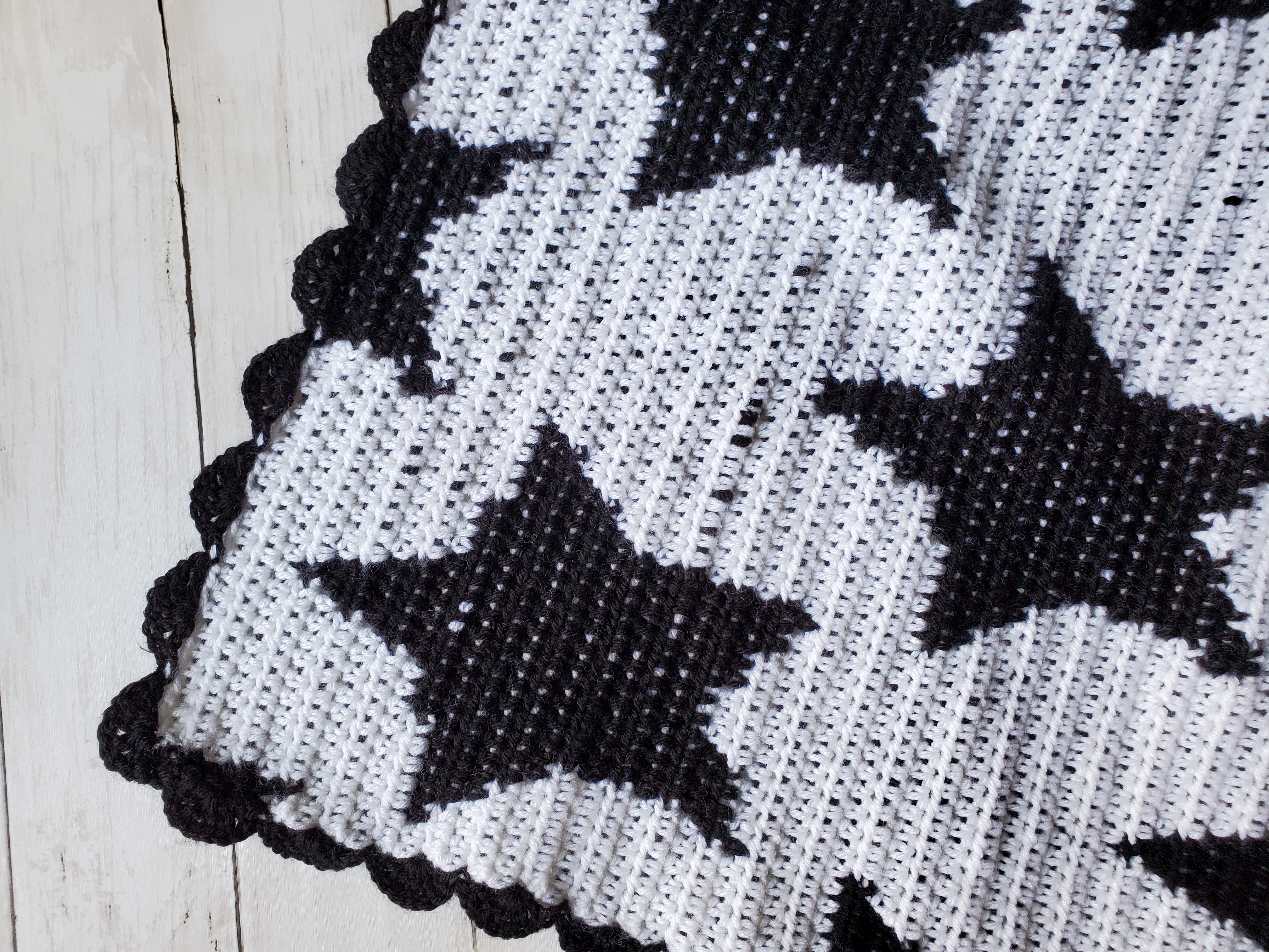 Corner shot of black and white star baby blanket with shell border